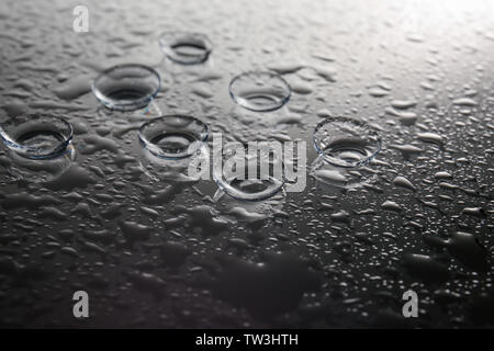 Contact lenses and drops of water on gray background Stock Photo