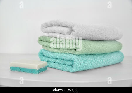 Stack of clean towels and soap on table Stock Photo