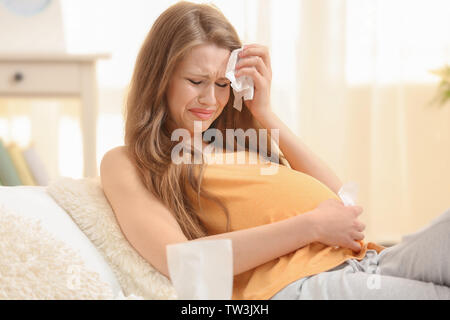 Beautiful pregnant woman crying in light room. Pregnancy hormones concept Stock Photo