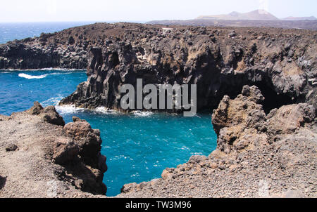 View on rugged rough coastline with sharp cliffs. lagoon with turquoise blue water, waves - Los Hervidereos, Lanzarote Stock Photo