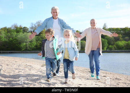 Happy grandparents playing with little children on river bank Stock Photo
