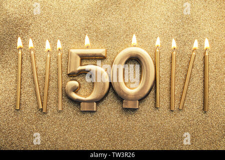 Number 50 gold celebration candle on a glitter background Stock Photo