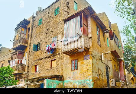 The dusty shabby living building, made of earthen brick; Arabian and English sign on the wall with inscription of street name - Sekket El-Mahgar, Isla Stock Photo