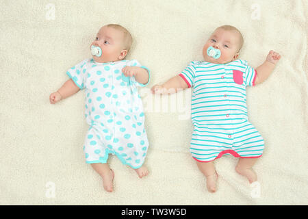 Beautiful baby twins lying with pacifiers on plaid Stock Photo