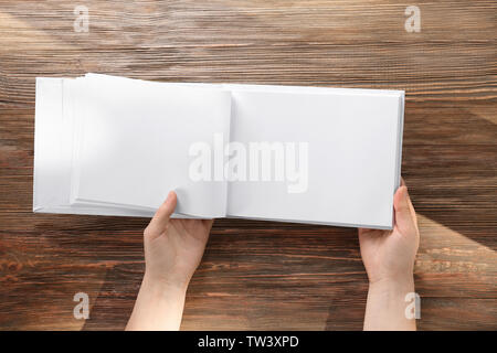 Female hands holding opened book with blank pages on wooden background Stock Photo