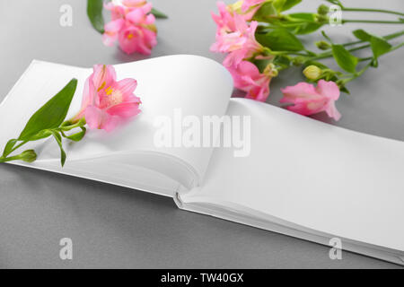 Open book with blank pages and beautiful flowers on gray background Stock Photo