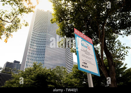A sign showing reserved spot for Blue SG car sharing electric car space in Singapore with skyscraper in the background. Stock Photo