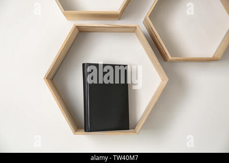 Shelf with blank book hanging on wall Stock Photo