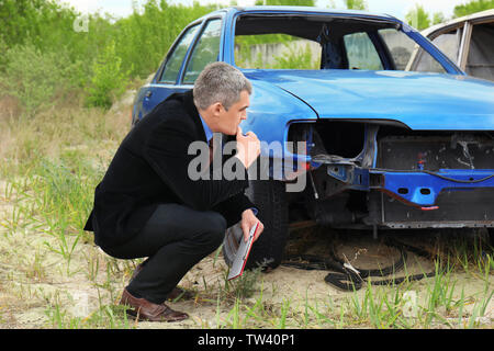 Insurance man checking broken car after accident Stock Photo