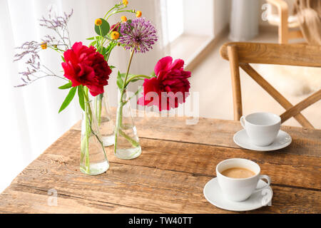 Beautiful flowers in vases as floral decor on wooden table Stock Photo
