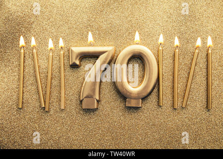 Number 70 gold celebration candle on a glitter background Stock Photo