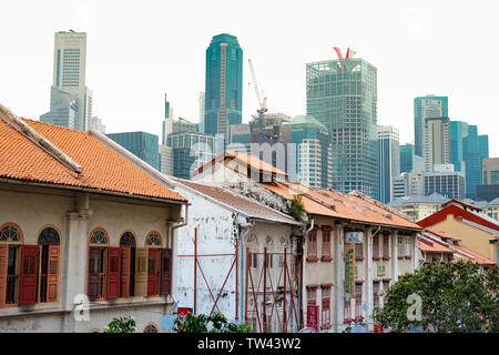 Traditional Singapore Shophouses with the city skyline in the background taken from China town district showing the contrasting architecture. Stock Photo