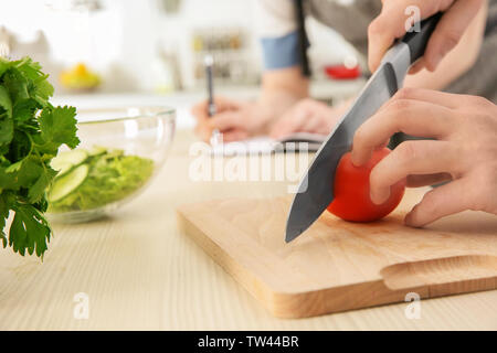 Chef teaching how to slice tomato on cutting board. Concept of cooking classes Stock Photo