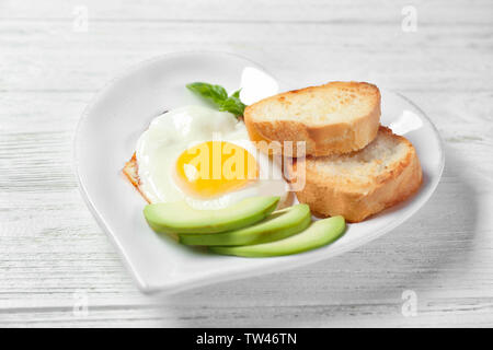 Delicious over easy egg with toasts and avocado on kitchen table Stock Photo