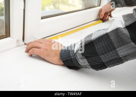 Young man installing window shades at home Stock Photo