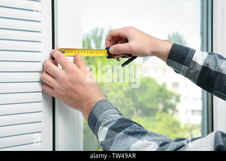 Young man installing window shades at home Stock Photo
