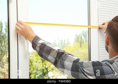 Young man installing window shades at home Stock Photo