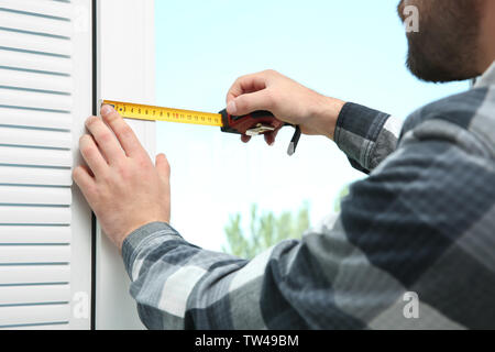 Young man installing window shades at home Stock Photo