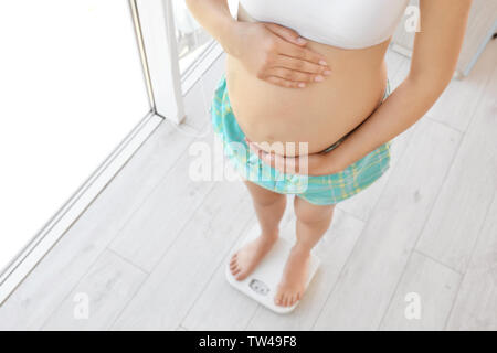 Pregnant woman standing on scales at home. Pregnancy weight gain concept Stock Photo