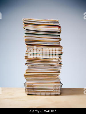 In, out tray on desk with tall stack of never ending office paperwork Stock Photo