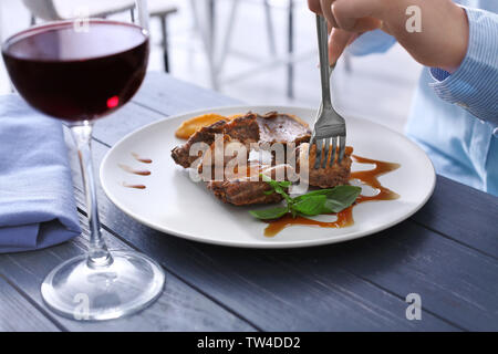 Young woman eating delicious ribs in restaurant Stock Photo