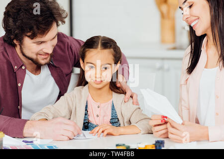 happy father smiling near cute daughter with paper plane at home Stock Photo