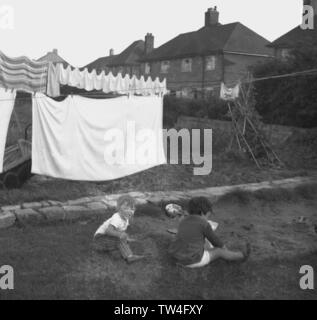 1960s, historical, two young boys playing by  sandpit in a back garden with washing hanging up on a line, England, UK. Stock Photo