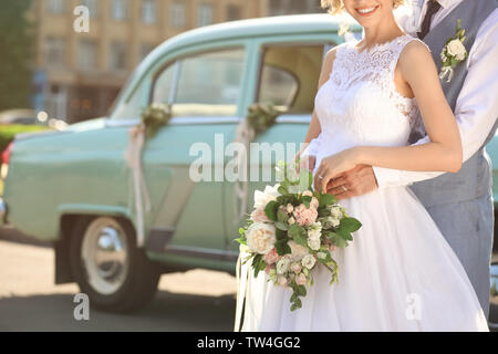 Happy wedding couple and decorated car on background Stock Photo