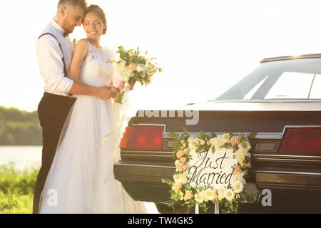 Happy wedding couple near decorated car on shore Stock Photo