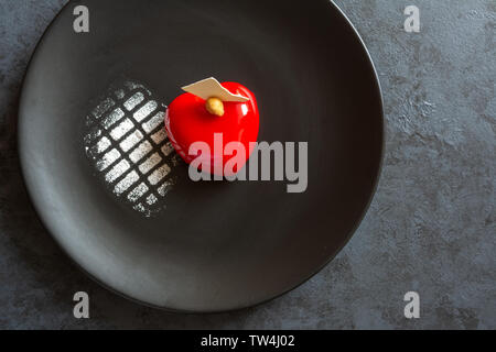 Currant cake in the shape of a red heart on a black plate. Stock Photo