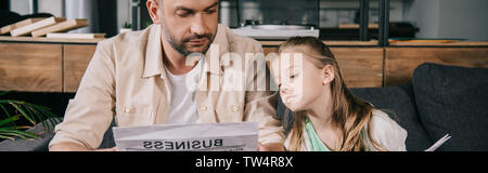 panoramic shot of father and adorable daughter reading business newspaper together Stock Photo