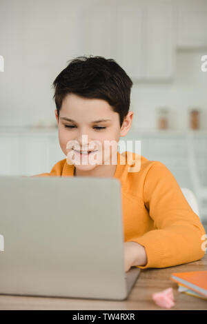 smiling attentive boy using laptop while doing schoolwork at home Stock Photo