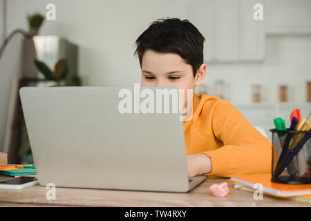 cute schoolkid using laptop while doing schoolwork at home Stock Photo