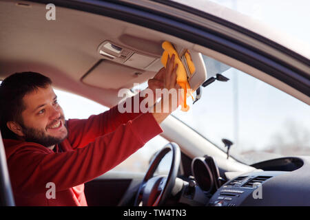 Image on side of happy male with orange rag washing mirror of car,close up Stock Photo