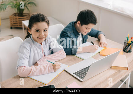 high angle view of cute brother and sister sitting at desk and doing homework together Stock Photo