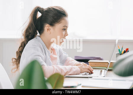 selective focus of adorable child using laptop while doing schoolwork at home Stock Photo