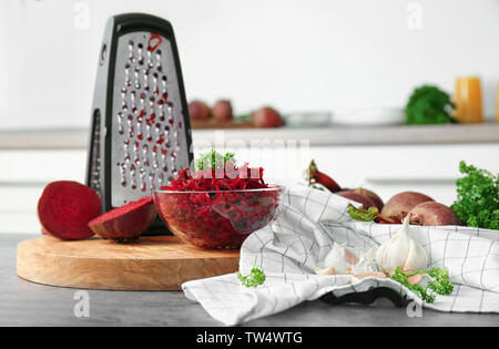 Fresh beetroot and grater on table in kitchen Stock Photo
