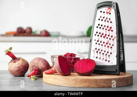 Fresh beetroot and grater on table in kitchen Stock Photo