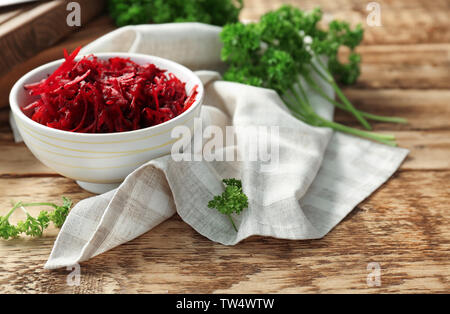 Bowl with grated beetroot on wooden table Stock Photo