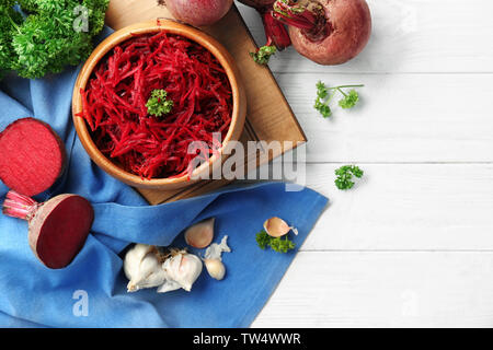 Wooden bowl with grated beetroot on table Stock Photo