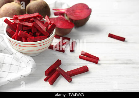 Bowl with sliced beetroot on white wooden table Stock Photo