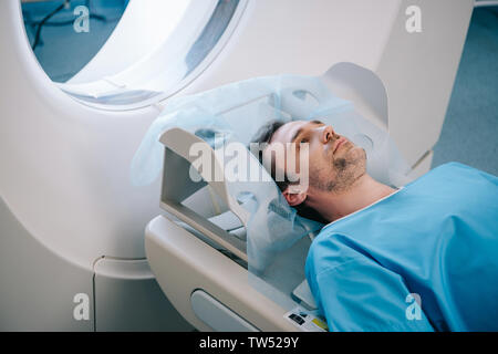 adult handsome man lying on ct scan bed during tomography test Stock Photo