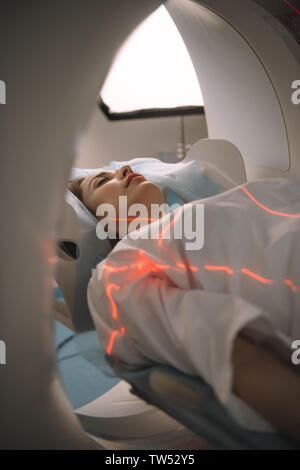 young woman lying on ct scanner bed during tomography diagnostics in hospital Stock Photo