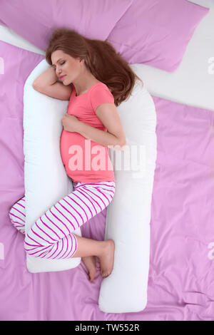 Beautiful pregnant woman sleeping with body pillow Stock Photo