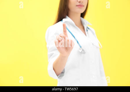 Young doctor using virtual screen, on color background Stock Photo