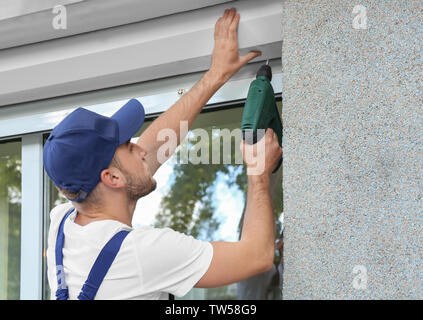 Man installing roller shutter on window Stock Photo