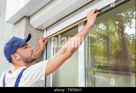 Man measuring window prior to installation of roller shutter outdoors Stock Photo