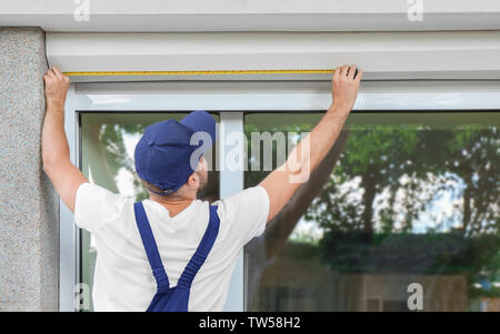 Man measuring window prior to installation of roller shutter outdoors Stock Photo