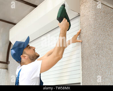 Man installing roller shutter on window Stock Photo