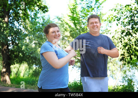 Overweight couple running in green park Stock Photo